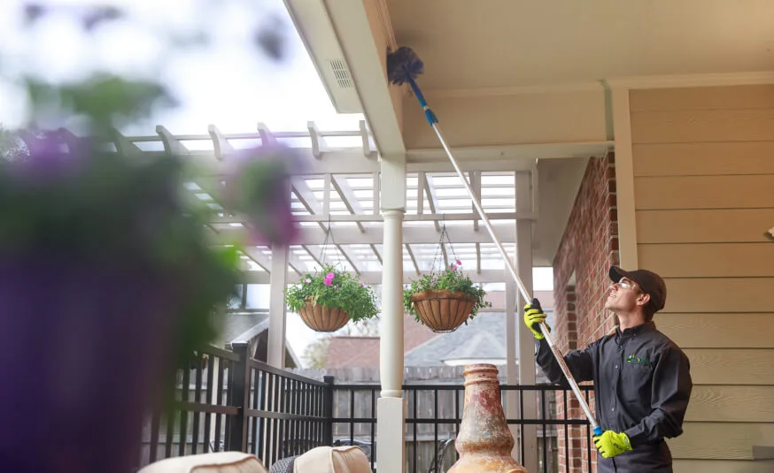 Florida Pest Technician cleaning the back porch area of cobwebs