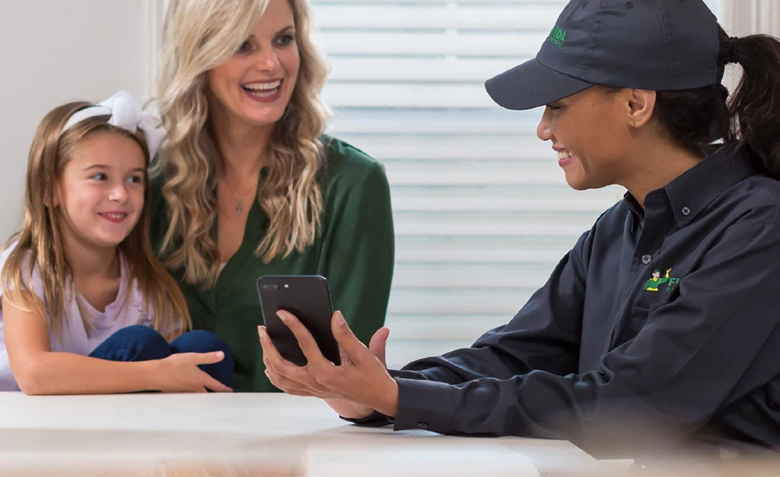 Florida Pest Control technician sitting at a table with a woman and her child